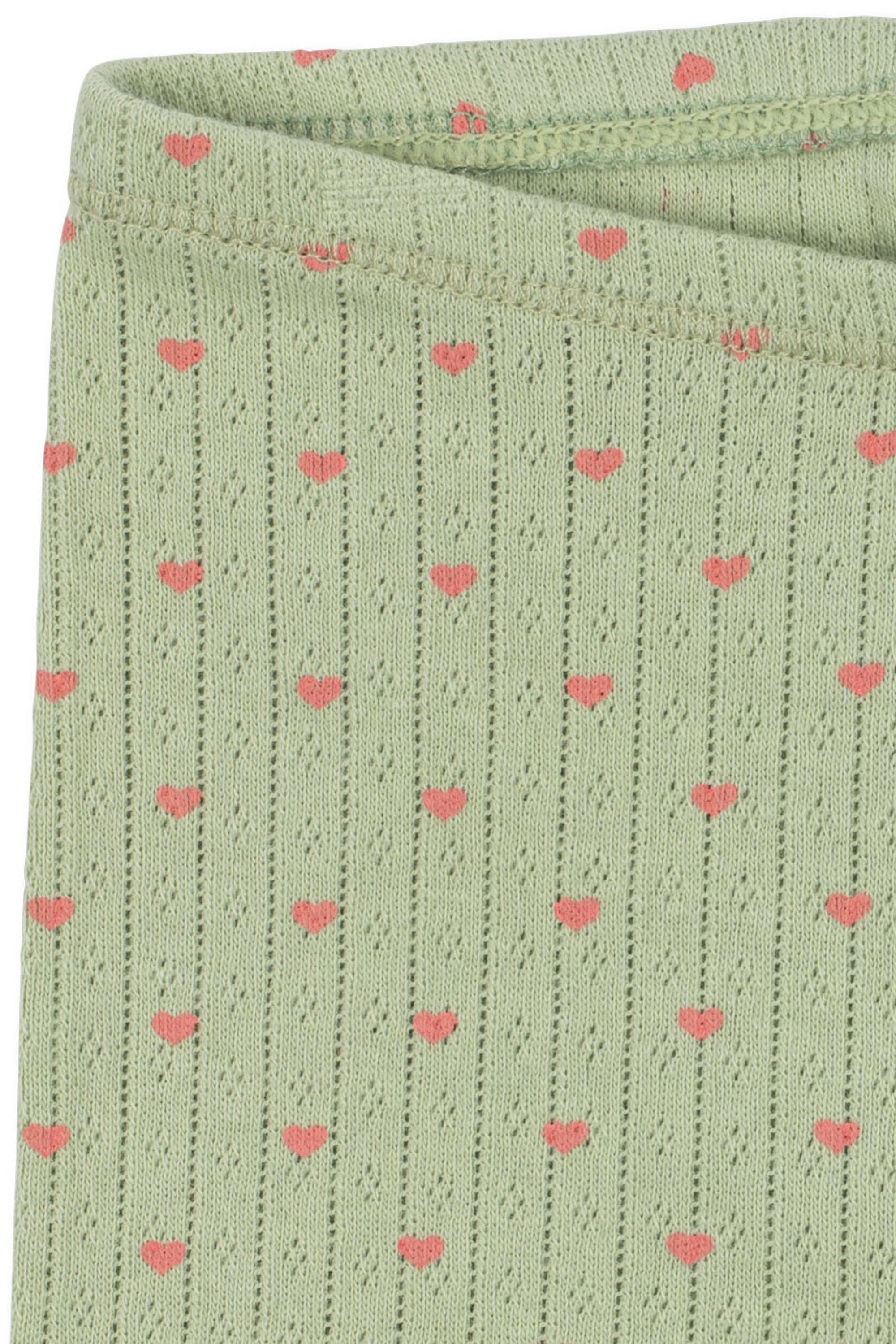 A close-up of a light sage green ribbed knit fabric with a repeating pattern of small pink hearts.
