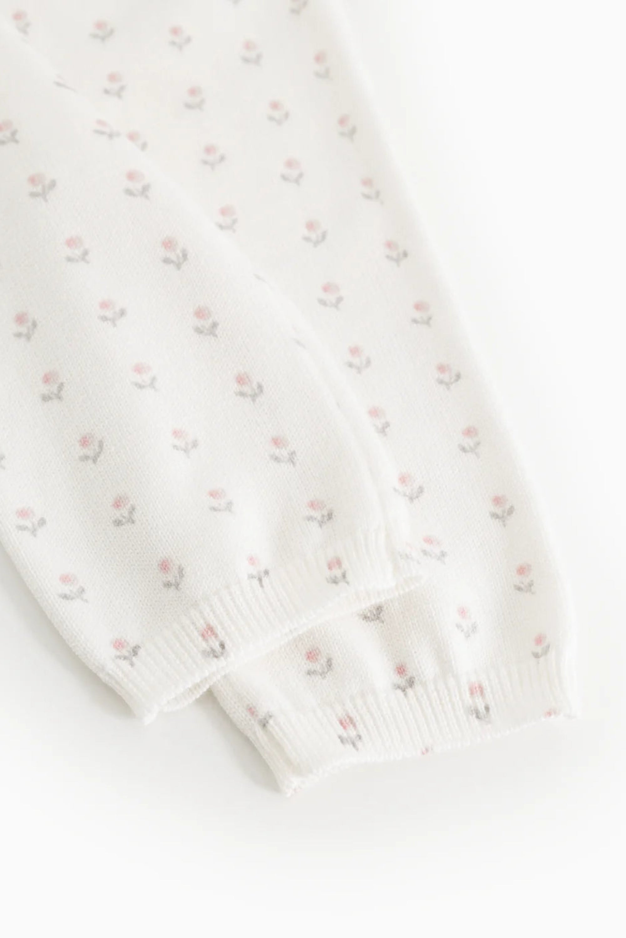 White fabric with subtle pink floral pattern on a white background