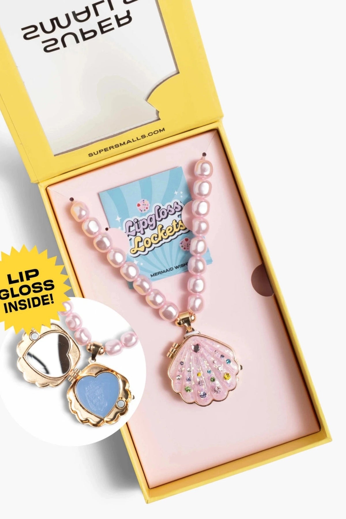 A pink pearl necklace with a clam-shell pendant containing rhinestones, presented in a yellow and pink gift box. A circular inset shows the inside of the clam pendant with a blue lip gloss layer and gold trim.